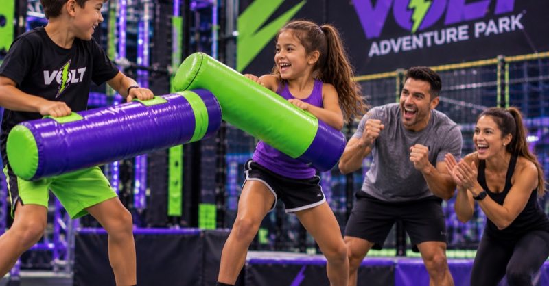 Kids battling on the Battle Beam while parents cheer